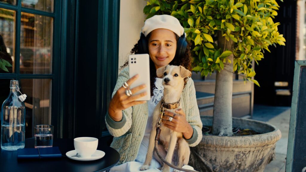 Young woman with headphones holding a puppy at a cafe