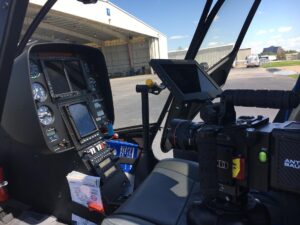Helicopter cockpit with a cinema camera and monitor facing the hangar