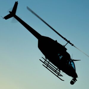 Helicopter with a nose gimbal silhouetted against the sky