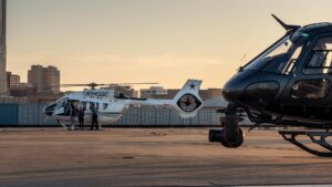 Two helicopters on the ramp at sunset, one with a camera gimbal