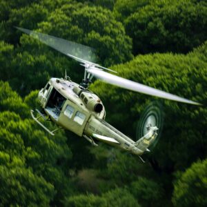 Army Huey flying over dense forest