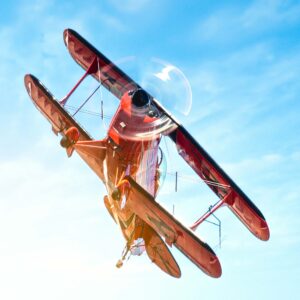 Red biplane flying against a blue sky