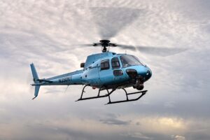 Light blue helicopter with a nose gimbal in flight