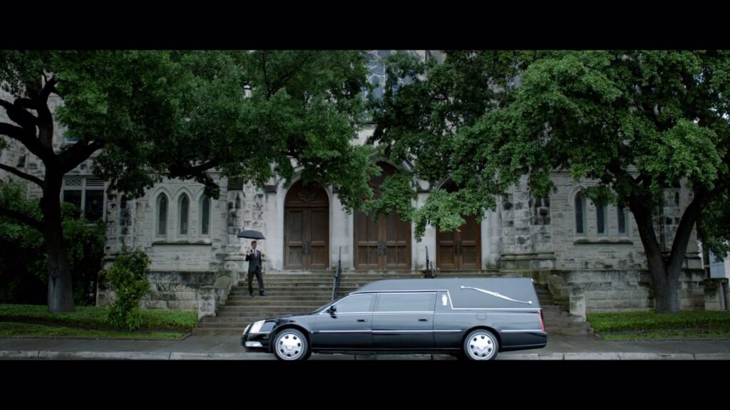 Black hearse parked in front of a stone church