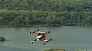 Orange and white Bell cargo drone flying over a lake