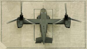 Overhead view of a V-22 Osprey with rotors spinning on a landing pad