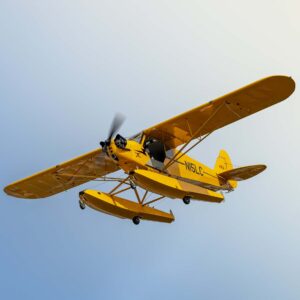 Yellow floatplane flying against a clear sky