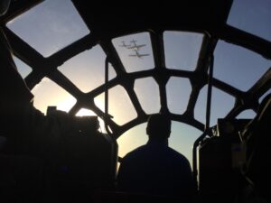Crew silhouetted inside the glass nose of a B-29 during an air-to-air shoot
