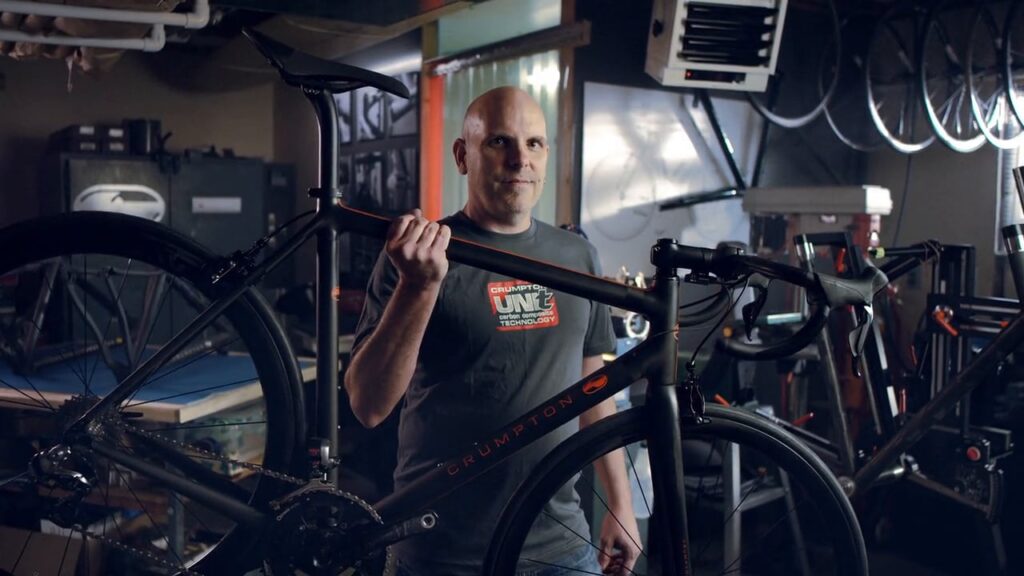 Shop owner standing among hanging bicycles in a bike shop