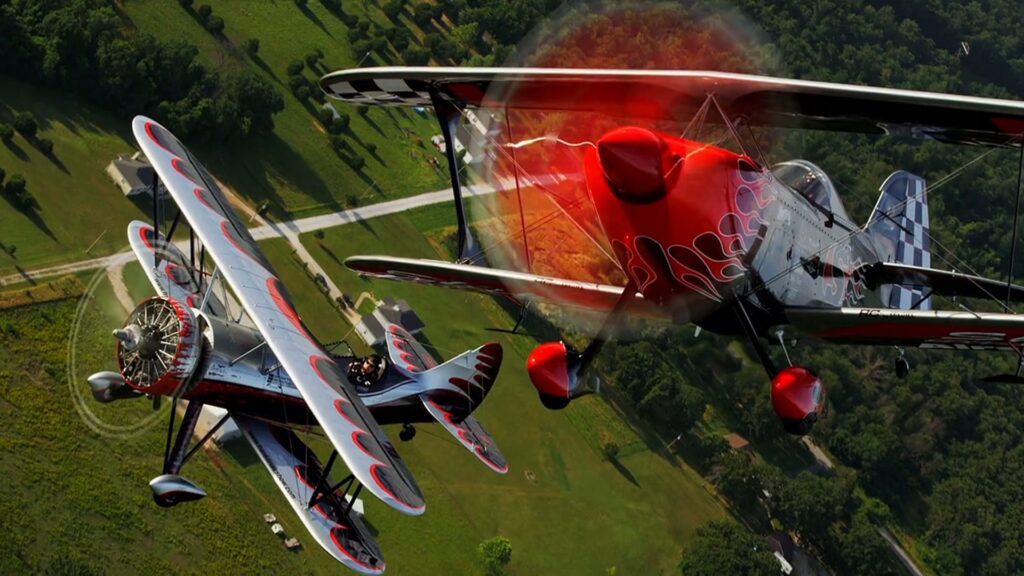 Two red and silver biplanes flying in formation during air-to-air photography
