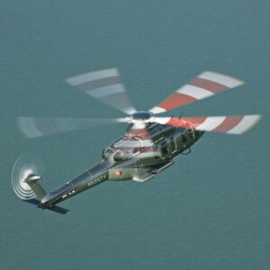 Dark helicopter flying over teal water