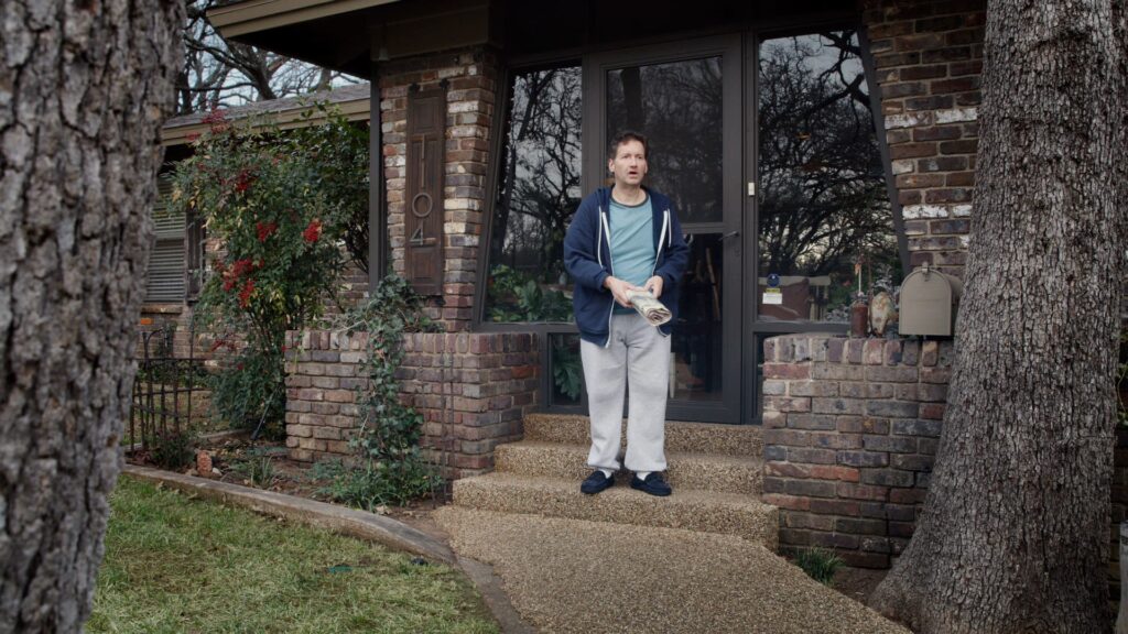 Man dressed in white standing at a brick garden gate
