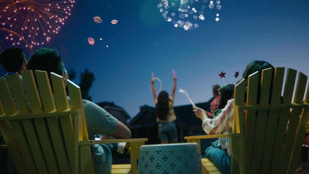 Group in lawn chairs watching fireworks overhead