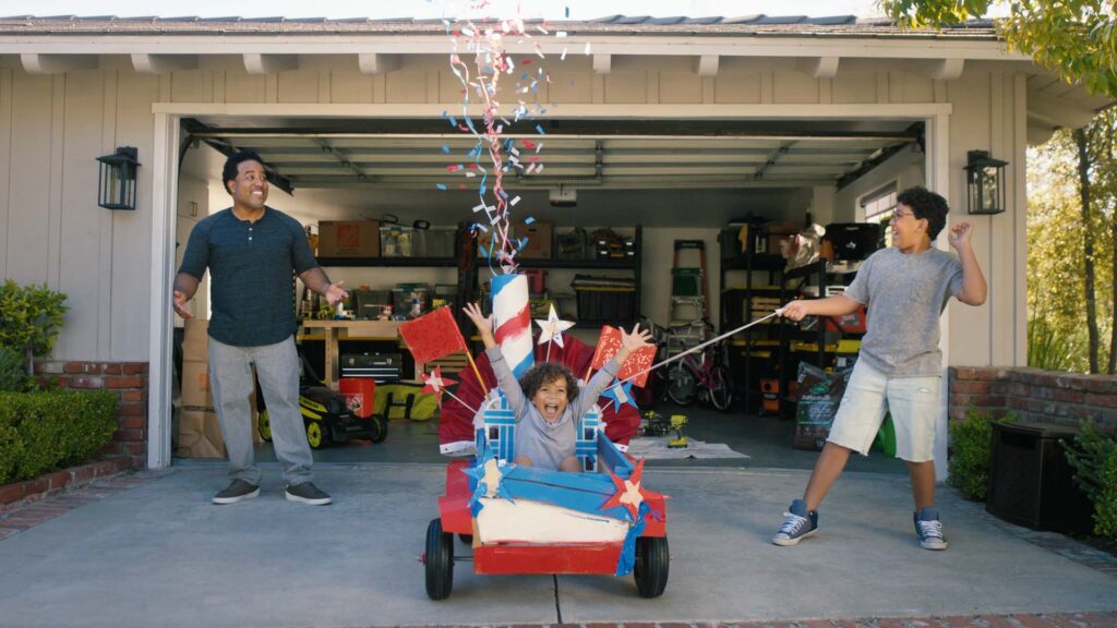 Two kids launching a homemade rocket from a wagon in a driveway