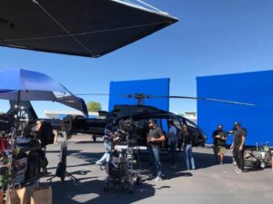 Film crew shooting a black helicopter in front of blue screens