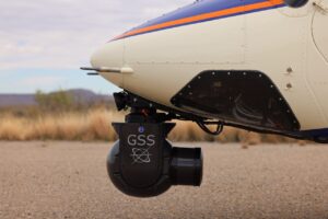 Close-up of a GSS camera gimbal on a cream helicopter nose